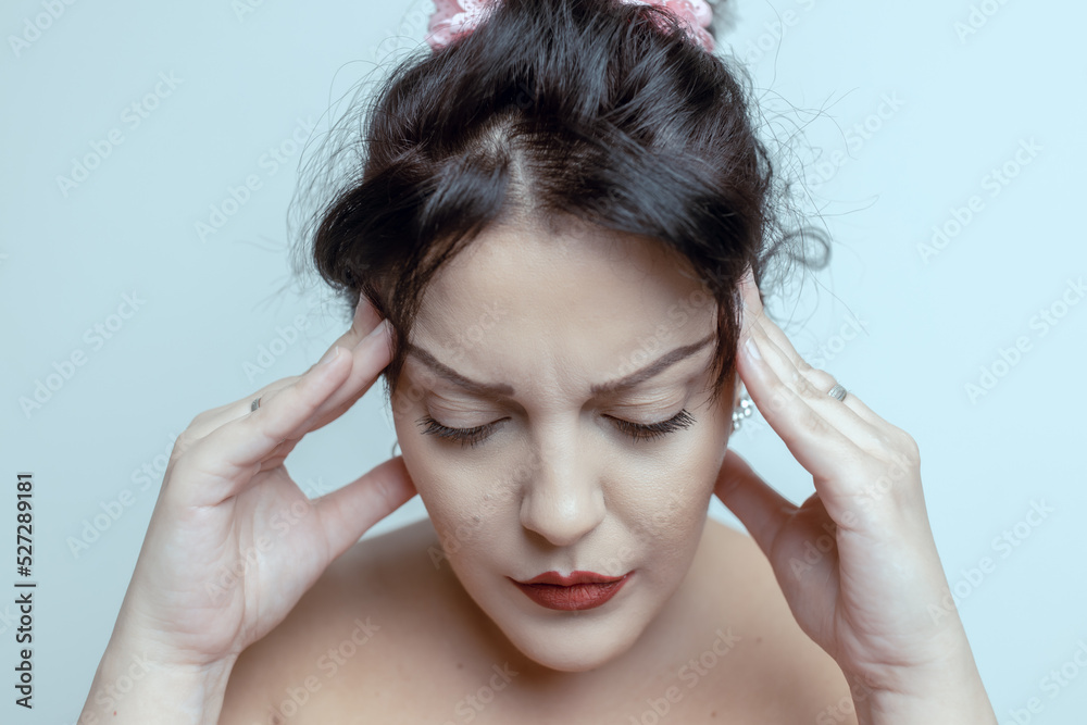 Fototapeta premium Stressed young woman touching her head and looking down in pain