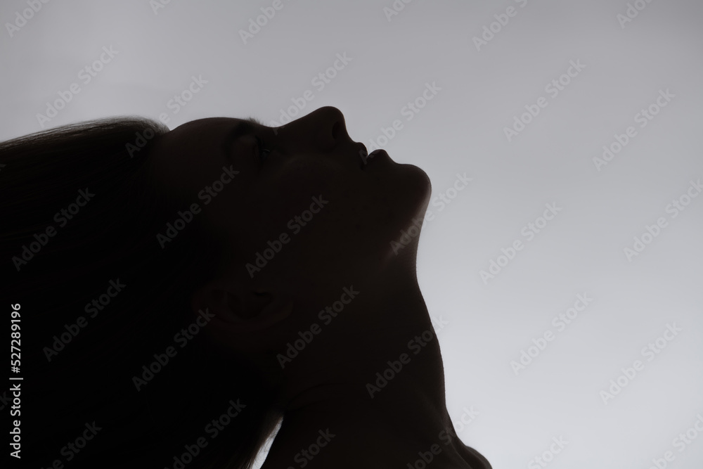 Fototapeta premium Beauty and fashion concept. Sensual woman black face and neck silhouette with flying hairs in white background with copy space