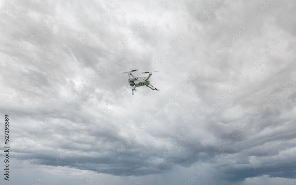 A high-tech drone in the sky Professional filming drone flies in the air at a low altitude against a blue sky and sea sandy beach. The drone makes photos. Modern new technology. A high-tech drone in the sky Professional filming drone flies in the air at a low altitude against a blue sky and sea sandy beach. The drone makes photos. Modern new technology.