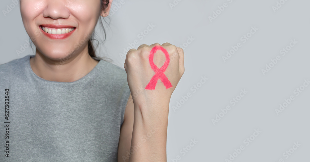 Asian woman are show Pink ribbon which draw by lip stick on back hand and making fist to encourage breast cancer patient. Breast cancer campaign in October month Asian woman are show Pink ribbon which draw by lip stick on back hand and making fist to encourage breast cancer patient. Breast cancer campaign in October month