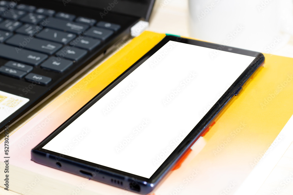 Smart phone with earphone and computer and notebook are on table . Smart phone with earphone and computer and notebook are on table .