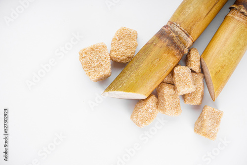 Sugar cane and brown sugar on a white background, space for text. Top view.