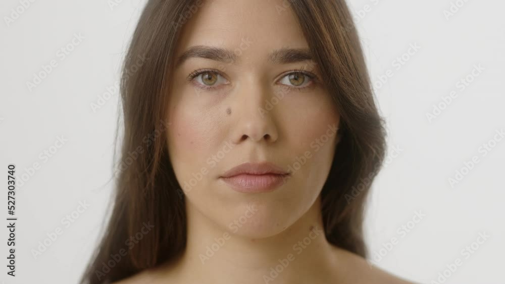 Beauty Woman face Portrait. Attractive Spa model Girl with Perfect Fresh Clean Skin. Hispanic Female with Brunette hair with naked shoulders opening her Beautiful Eyes and looking at camera with calm
