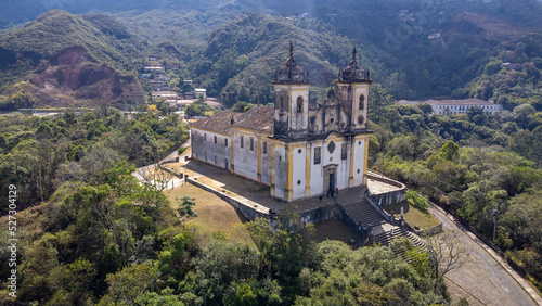 Visão panoramica de igreja em cidade histórica de Ouro Preto Minas Gerais em meio a montanhas e céu nublado construções e casas antigas ao fundo © Rayan