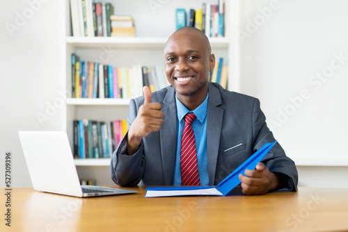 Smart african american mature businessman showing thumb up at desk at office