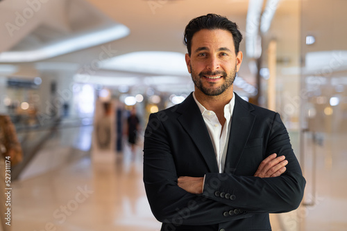 Happy Hispanic businessman smiling with arms crossed