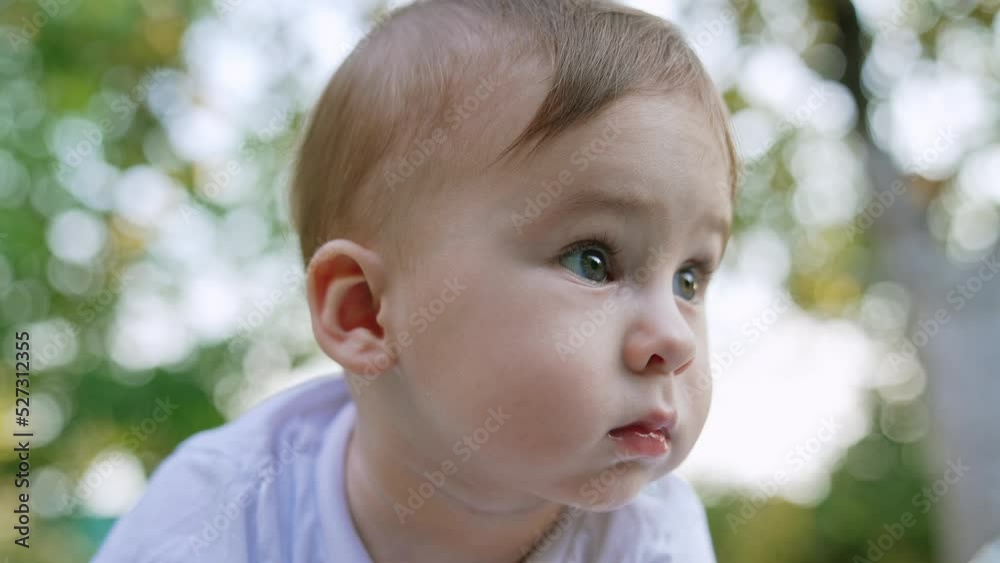 Adorable face of a child looking aside. Cute toddler staying outdoors. Close up. Blurred backdrop. Adorable face of a child looking aside. Cute toddler staying outdoors. Close up. Blurred backdrop.