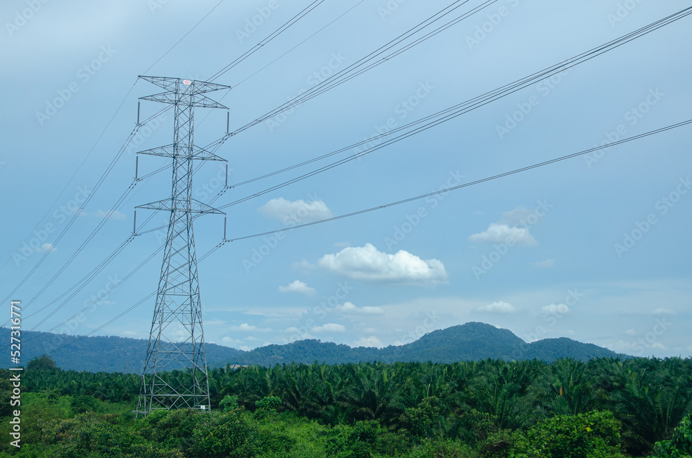 A distribution substation with power lines and transformers located in a village with a mountain backdrop A distribution substation with power lines and transformers located in a village with a mountain backdrop