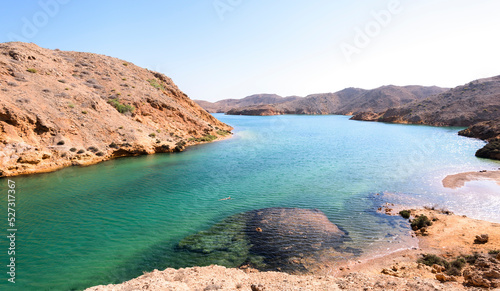 Woman swimming alone in a fjord-like in Sultanate of Oman, Middle East, Arabian Peninsula 