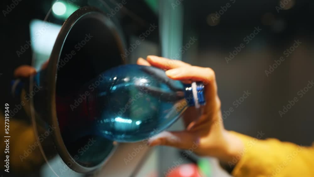 Woman puts bottle in automatic bottle recycling machine. Reverse vending recycling machine.