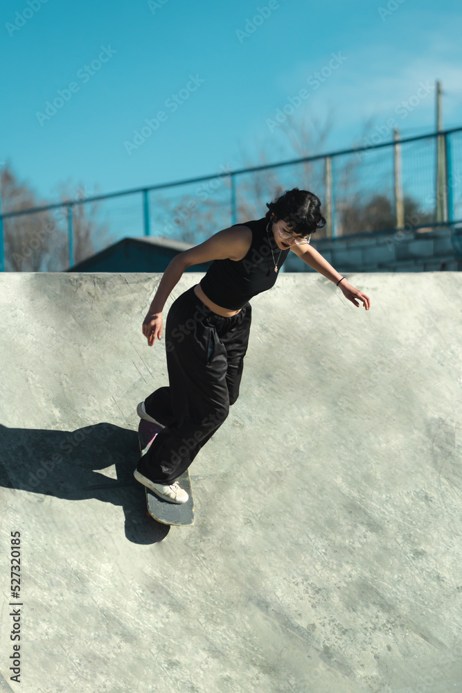 Young skater girl dressed all in black on skate park