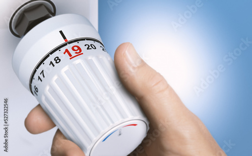 Man reducing energy consumption by setting thermostat temperature to 19 degrees. photo