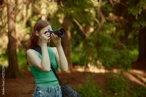 A beautiful girl enjoys nature and takes photos. Young woman wearing green top.