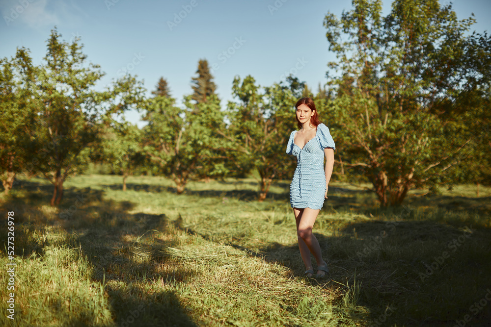 Young beautiful woman walking alone in the forest in blue dress. Enjoying sun and fresh air. Young beautiful woman walking alone in the forest in blue dress. Enjoying sun and fresh air.