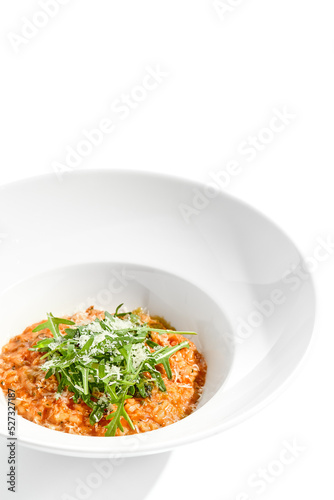 Vegan tomato risotto with ruccola on white plate. Italian dish - veggie risotto isolated on white background. Plant based dining. Clean eating in restaurant menu. Eat less meat. Vegetarian lunch.