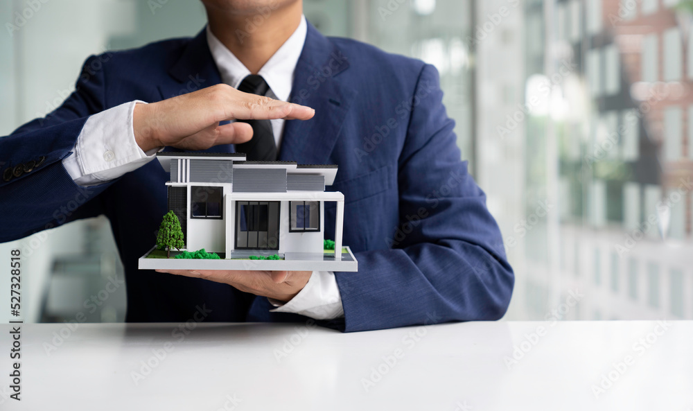 businessman or home insurance broker Holding a small model house offers home insurance. house trading businessman or home insurance broker Holding a small model house offers home insurance. house trading