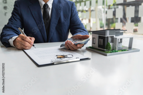 Sign home sales contracts, real estate agent employment contracts, contract documents, home loan insurance, and purchase approval for customers with house designs and keys on the table.