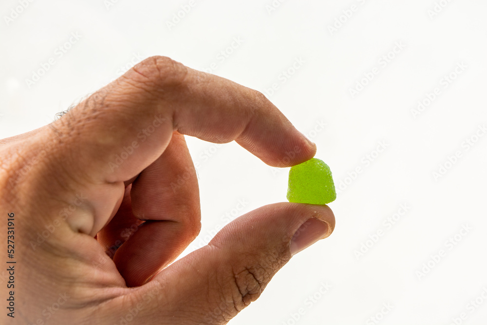 male hand holding gum drop, isolated on white background male hand holding gum drop, isolated on white background