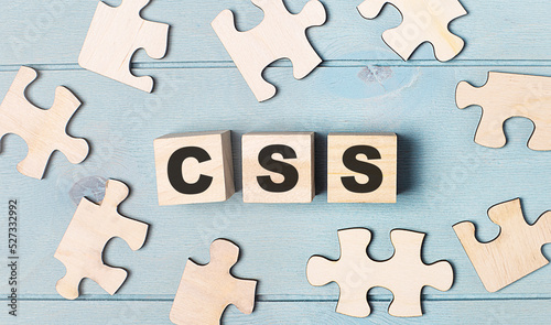 Blank puzzles and wooden cubes with the text CSS Cascading Style Sheets lie on a light blue background.