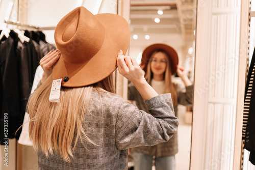 A smiling young shopaholic woman tries on clothes in a shopping mall store, walks through boutiques. Consumerism is a modern problem of society. Anti-environmental photo