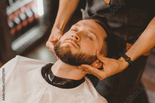 Foto Barber massages man face to improve hair growth and skin care