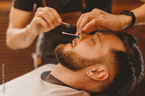 Removes hair from nose of man with wax master barber, depilation beauty procedure