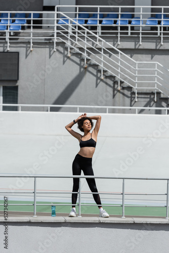 full length of african american sportswoman standing with closed eyes and hands above head. © LIGHTFIELD STUDIOS