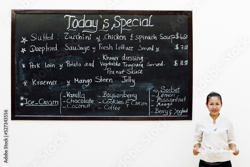 Waitress stands by chalkboard featuring the day's specials at a hotel restaurant. Siem Reap, Cambodia. photo