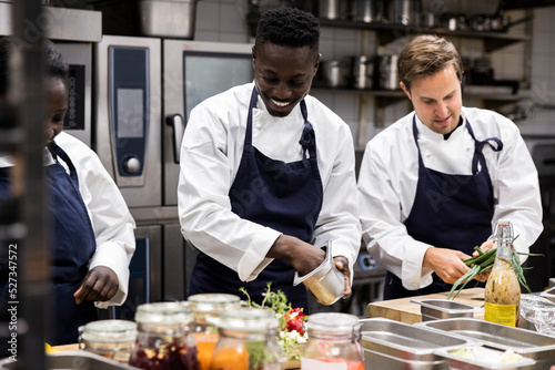 Chefs talking while preparing food in restaurant kitchen photo