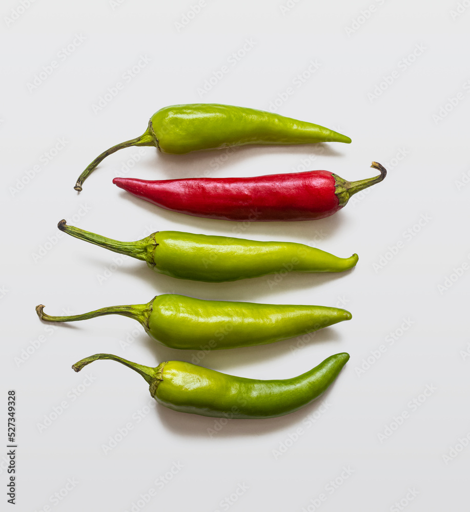 Hot chili peppers, green and red, on a light background Hot chili peppers, green and red, on a light background