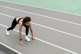 high angle view of african american runner standing in low start pose on track.