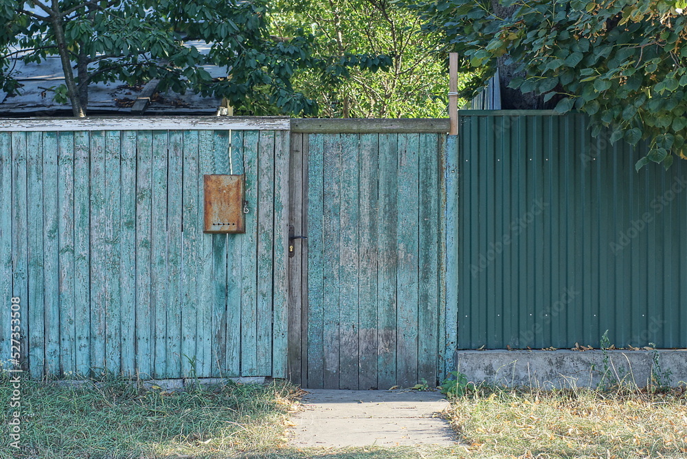 one closed gray green wooden door on a rustic fence wall in the street