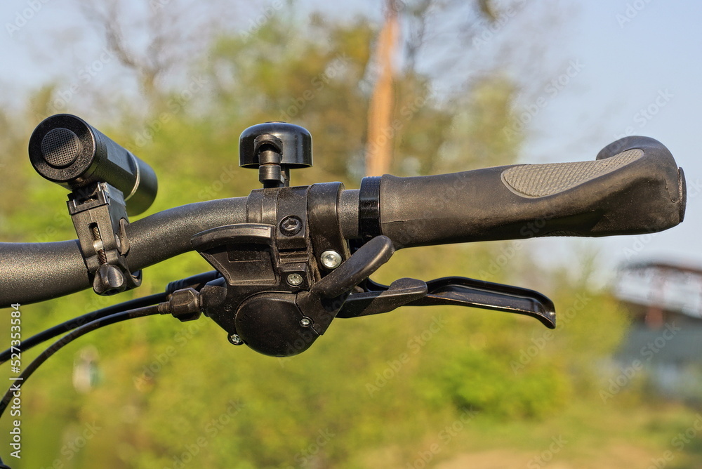 part of the bike from a black metal handlebar with a plastic handle and a brake with a cable on the street on a green background part of the bike from a black metal handlebar with a plastic handle and a brake with a cable on the street on a green background