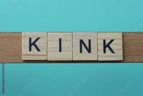 word kink made from wooden gray letters lies on a green background photo