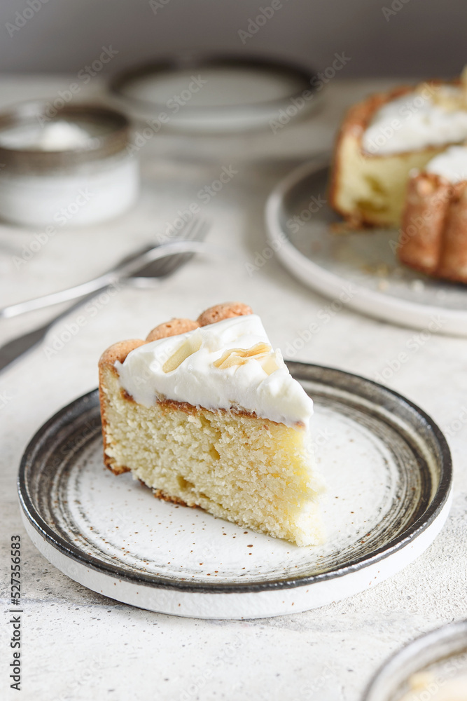 Slice of Homemade Coconut Buttermilk Pound Cake glazed whipped cream and coconut flakes on gray concrete background. Selective focus Slice of Homemade Coconut Buttermilk Pound Cake glazed whipped cream and coconut flakes on gray concrete background. Selective focus