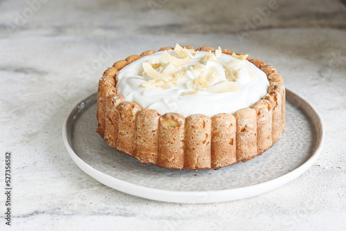 Homemade Coconut Buttermilk Pound Cake glazed whipped cream and coconut flakes on gray concrete background. Selective focus