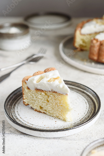 Slice of Homemade Coconut Buttermilk Pound Cake glazed whipped cream and coconut flakes on gray concrete background. Selective focus