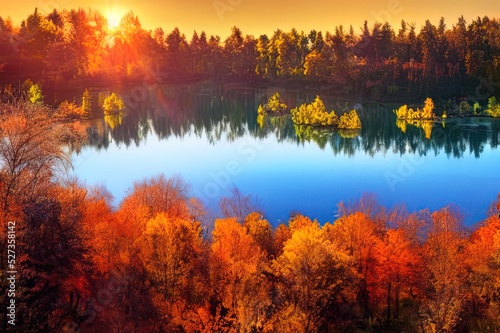 A beautiful autumn golden forest is reflected in the calm water of the lake. Autumn tranquil mood. Natural wallpaper