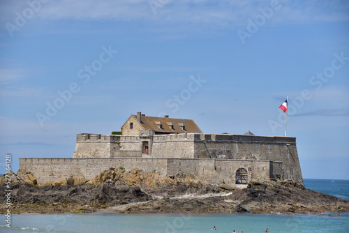 Ein Fort am Atlantik in Frankreich in der Totalen. Die französische Flagge ist sichtbar. Der Himmel ist Blau und das Meer ist am Fuß des Schlosses sichtbar photo