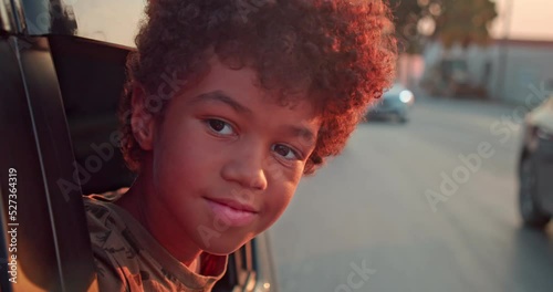 The boy looks out of the car window and looks into the camera, slow motion shooting at speed.