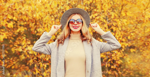 Autumn portrait stylish happy smiling woman wearing gray coat, round hat posing on yellow leaves background