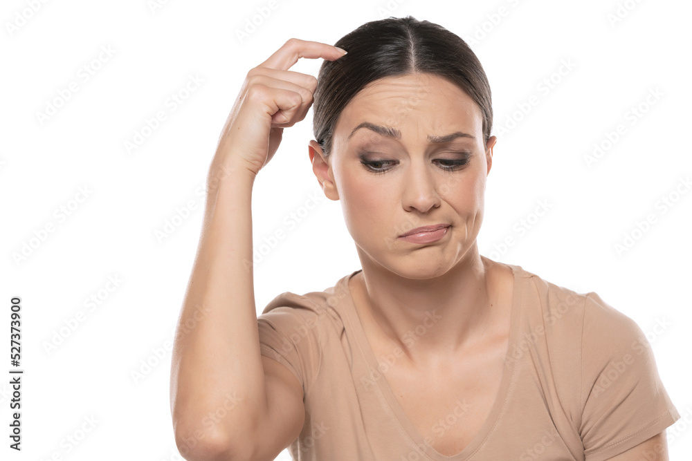 closeup portrait headshot of cute thoughtful woman looking down, scratching her head, isolated on white studio wall background closeup portrait headshot of cute thoughtful woman looking down, scratching her head, isolated on white studio wall background