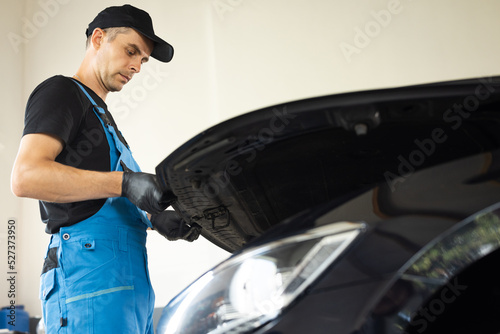 Automotive mechanic man open a car hood and check up the engine. Vehicle service manager worker work in mechanics garage, check and maintenance to repair the motorcar car in workshop