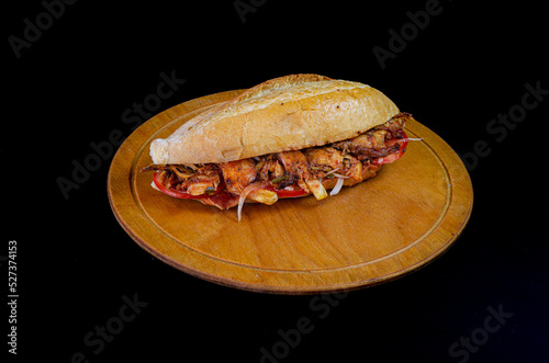 Chicken doner kebab in bread. Doner kebab in bread on wooden board on black background.
