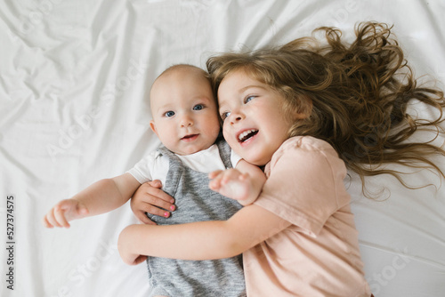 Girl (2-3) hugging baby brother (6-11 months)