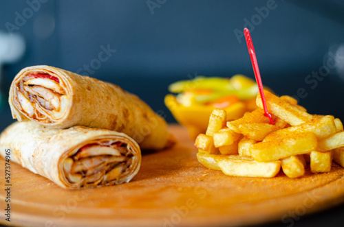 Doner kebab in lavash bread. Close-up delicious chicken doner burrito on black background. Potato chips. selective focus
