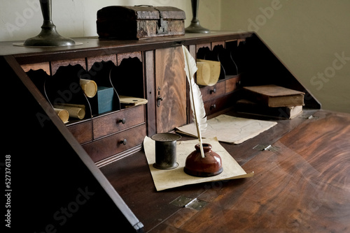 Quill pen with ink well on old wooden desk photo