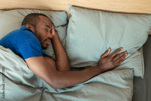 African Man Sleeping Alone Touching Pillow Lying In Bed Indoors