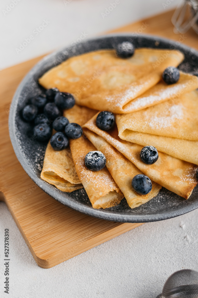 pancakes on a plate, sprinkled with powdered sugar, with berries. near a small sieve, berries and eggs. light background
pancakes on a plate, sprinkled with powdered sugar, with berries. near a small sieve, berries and eggs. light background