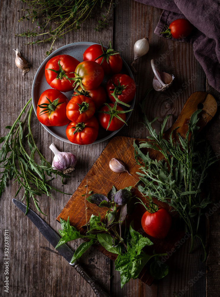 Fresh tomatoes and greens on a rustic table. View from above Fresh tomatoes and greens on a rustic table. View from above
